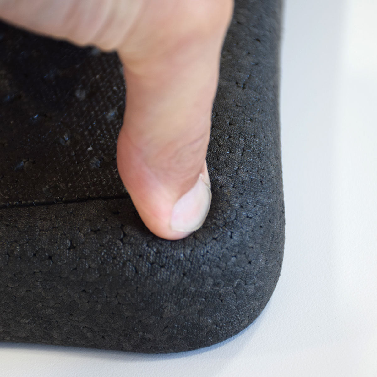 Close-up of a hand pressing down on kneeler to demonstrate cushioning